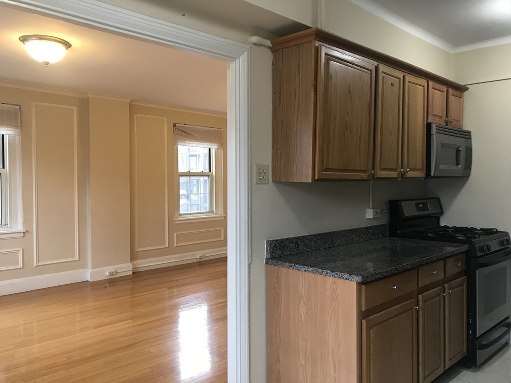 1450 Beacon Street, Unit 342 Brookline, MA 02446 - Photo 14 of 16 a kitchen with stainless steel appliances granite countertop a stove a sink and a microwave