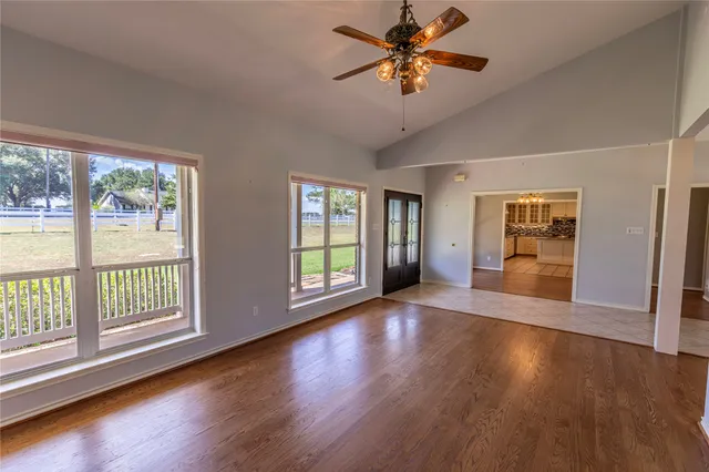 a view of an empty room with a window and wooden floor