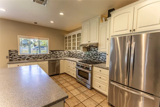 a kitchen with granite countertop a refrigerator stove and sink
