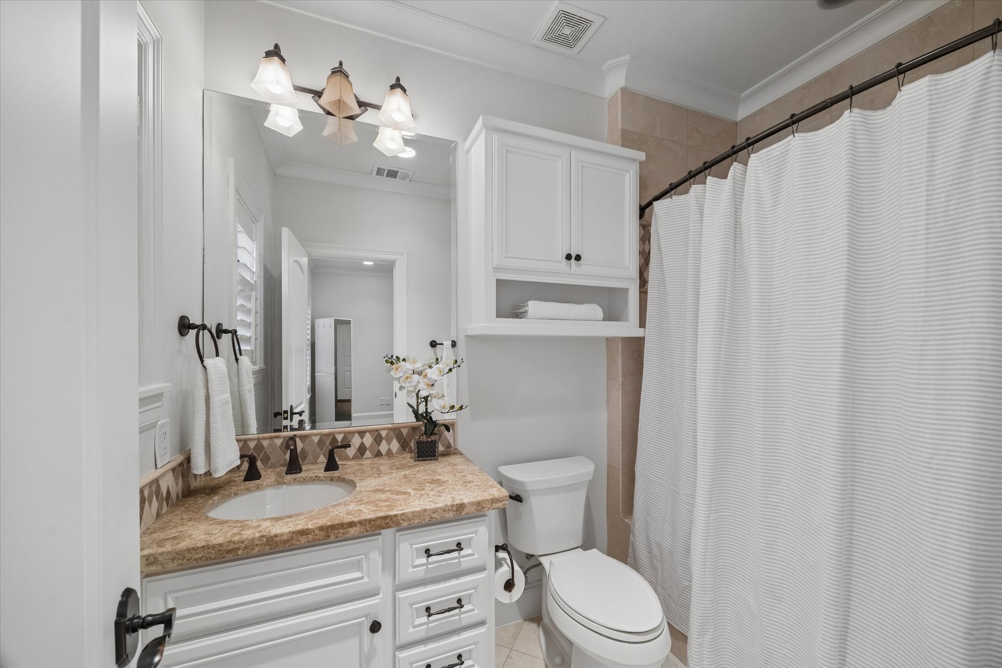 4511 Merrie Lane Bellaire, TX 77401 - Photo 38 of 46 a bathroom with a granite countertop sink toilet a mirror and shower curtain