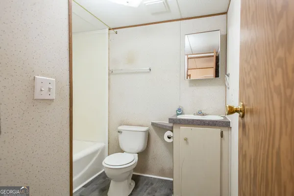 a bathroom with a granite countertop toilet a sink and a mirror