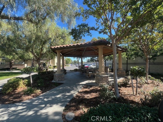10375 Church Street, Unit 106 Rancho Cucamonga, CA 91730 - Photo 23 of 26 a view of a patio with table and chairs under an umbrella with large trees