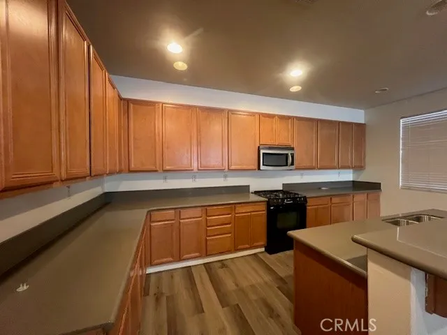 a kitchen with stainless steel appliances granite countertop a sink stove refrigerator and cabinets