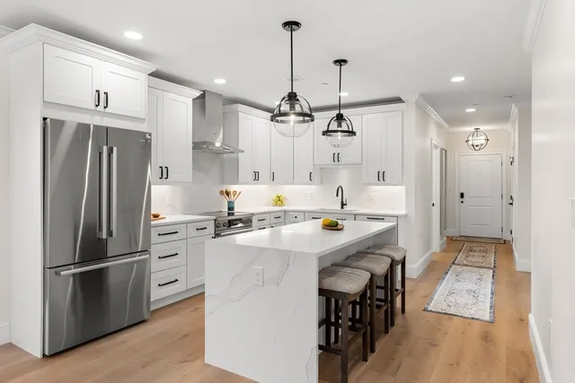 a kitchen with kitchen island a refrigerator a stove a sink and a wooden floor