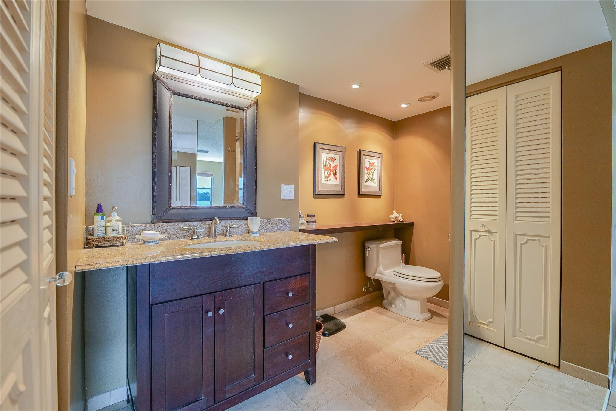 3930 Inverrary Boulevard, Unit 608D Lauderhill, FL 33319 - Photo 23 of 65 a bathroom with a granite countertop toilet sink and mirror