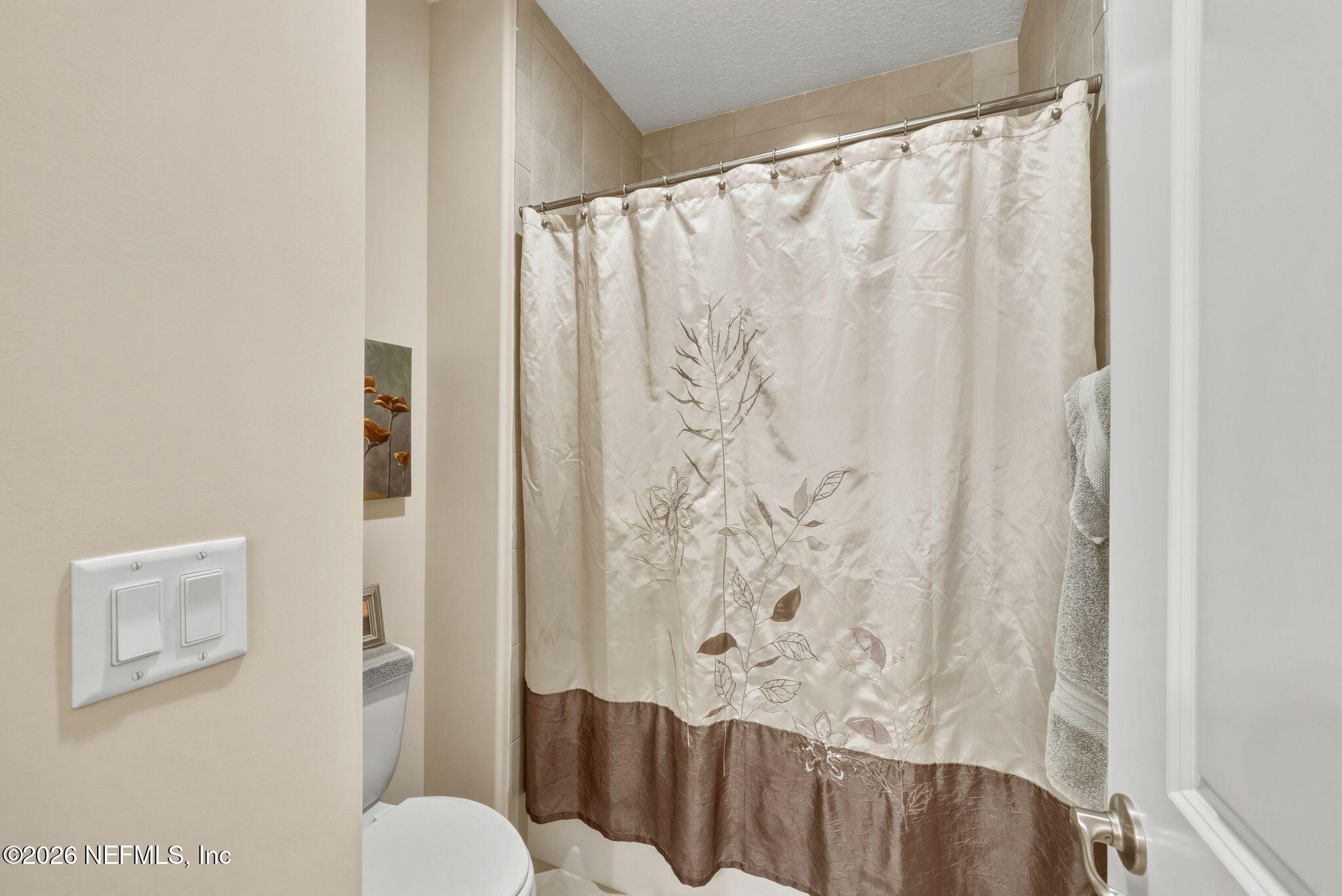 334 Athens Drive St. Augustine, FL 32092 - Photo 26 of 57 a bathroom with a toilet and shower curtain