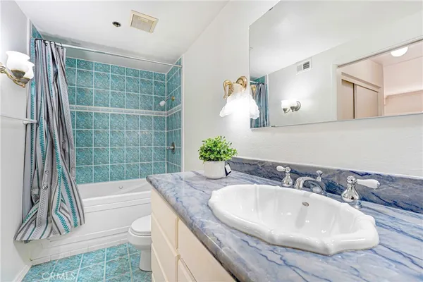 a bathroom with a granite countertop sink a toilet and shower