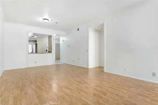 a view of an empty room with wooden floor and a mirror