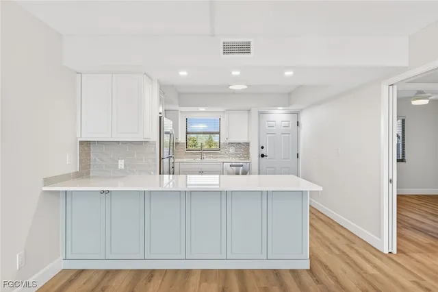 a kitchen with kitchen island white cabinets and stainless steel appliances