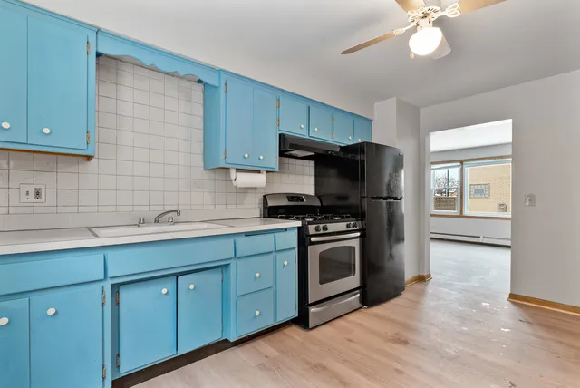 a kitchen with stainless steel appliances granite countertop a sink a stove a refrigerator cabinets and a window