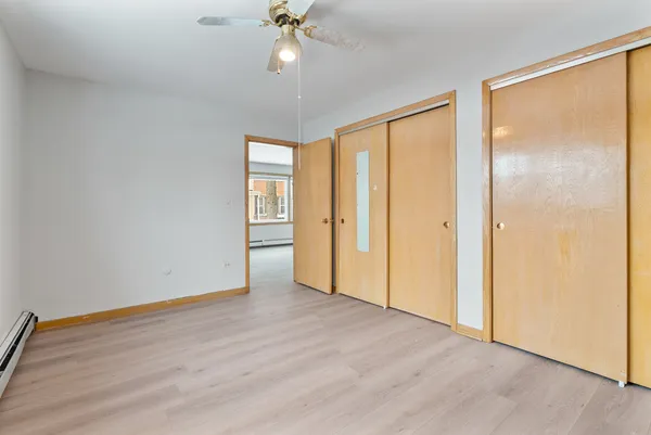 an empty room with wooden floor fan and windows