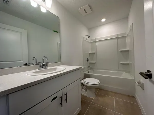 a bathroom with a sink a toilet a mirror a vanity and bathtub