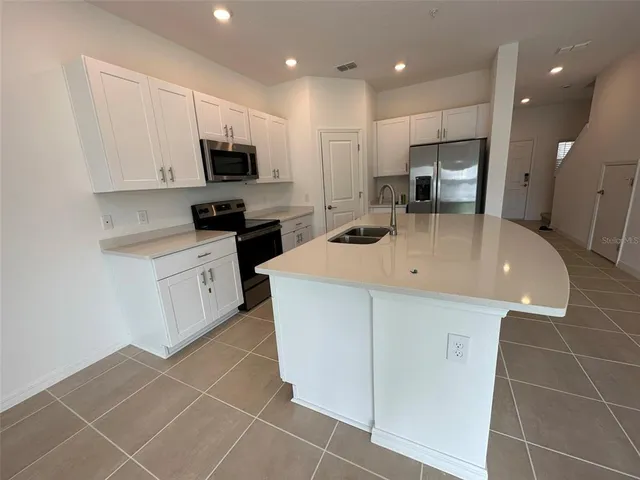 a kitchen with stainless steel appliances a sink a stove a microwave a sink a refrigerator and cabinets