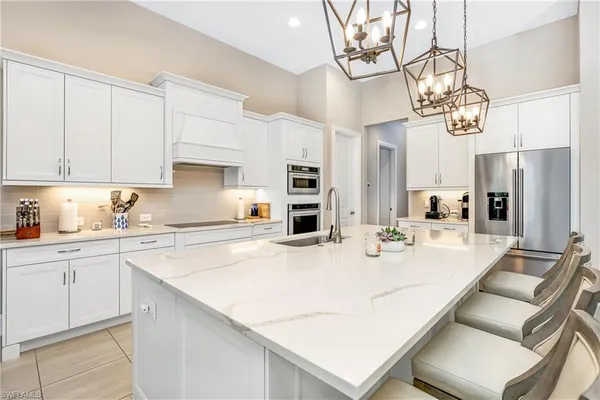 a kitchen with stainless steel appliances granite countertop a sink a stove a refrigerator a white table and chairs