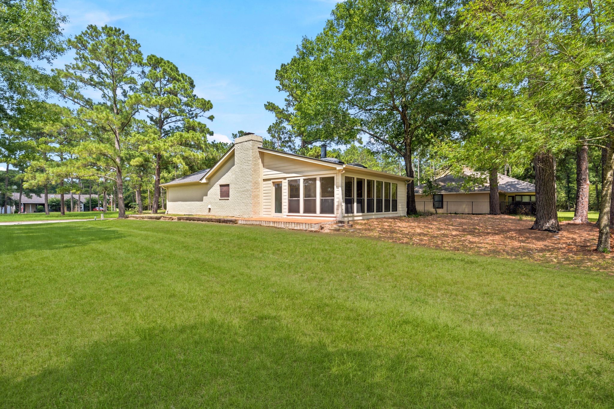 22509 Pebble Beach Way Point Blank, TX 77364 - Photo 27 of 30 Rear elevation with mature trees and a sprinkler-equipped yard