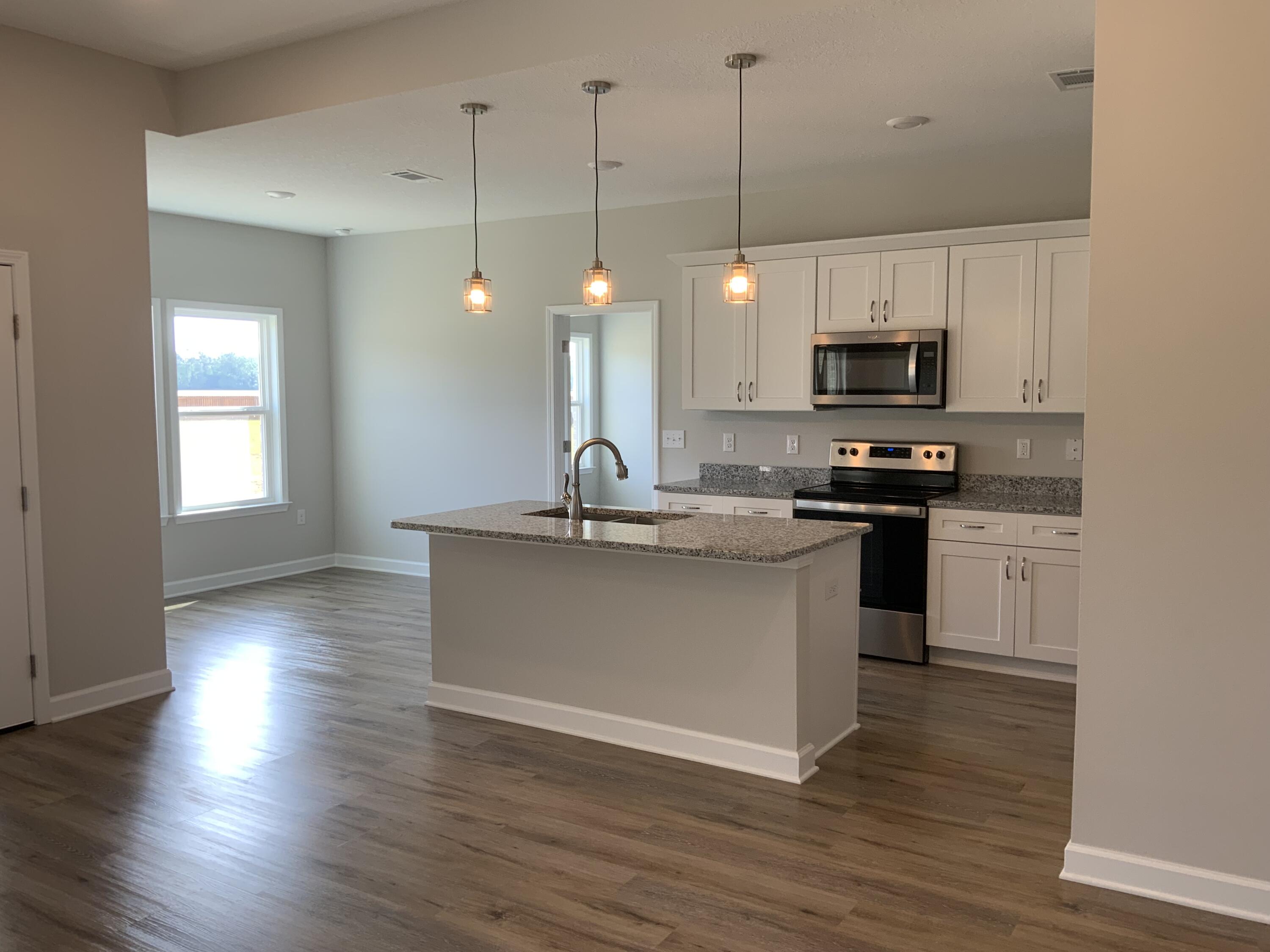 5229 Griffith Mill Road Baker, FL 32531 - Photo 4 of 10 a kitchen with kitchen island a sink cabinets and wooden floor