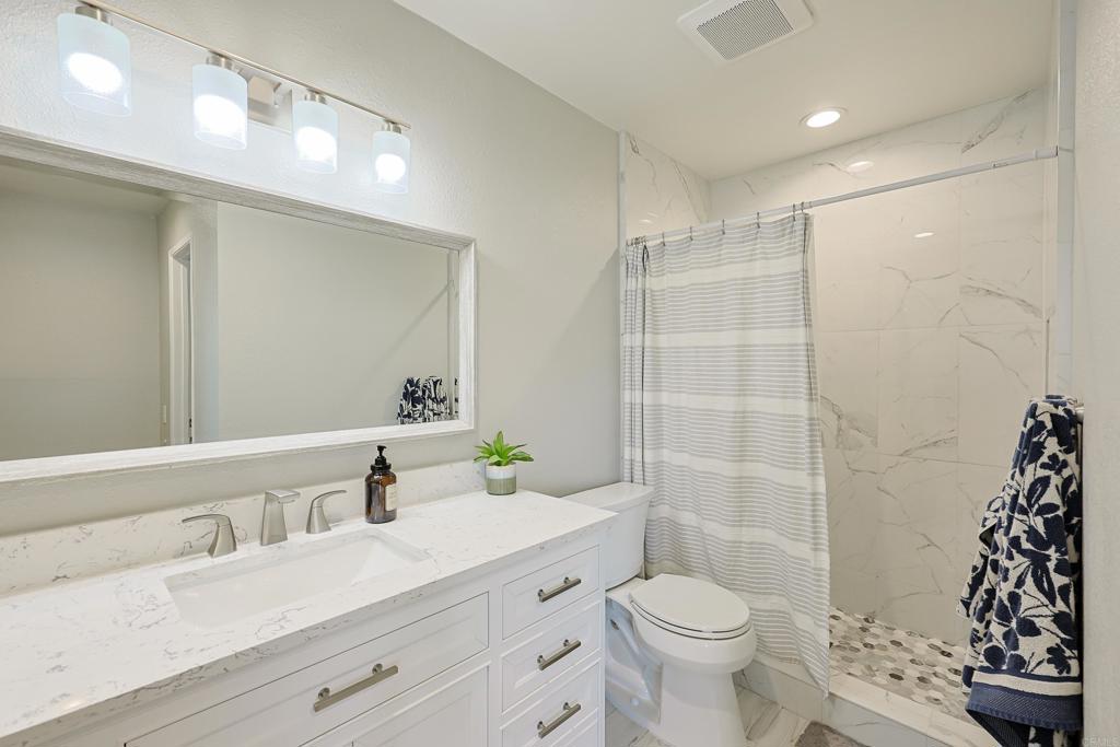 10225 Molino Road Santee, CA 92071 - Photo 25 of 53 a bathroom with a granite countertop sink a toilet a mirror and shower