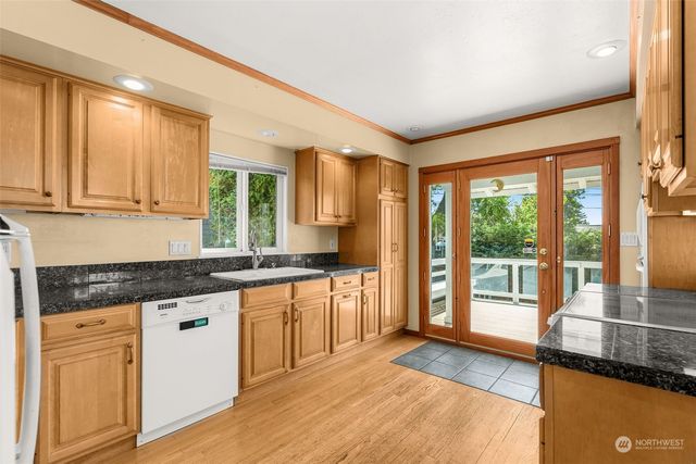a kitchen with granite countertop wooden floors stainless steel appliances and a counter space