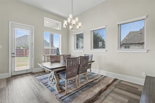 a dining room with wooden floor a chandelier a wooden table and chairs