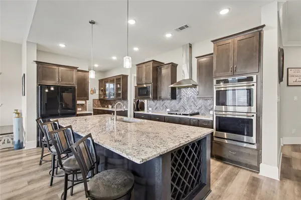 a kitchen with stainless steel appliances granite countertop a kitchen island a stove a table and chairs