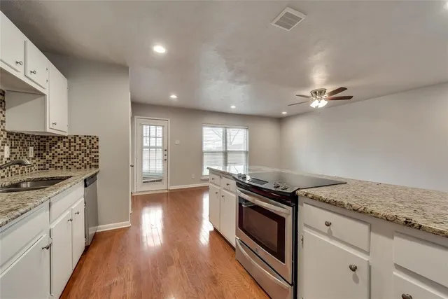 a kitchen with granite countertop stainless steel appliances a stove cabinets and wooden floor