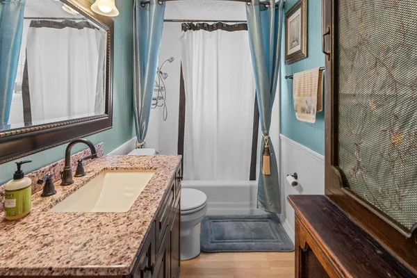 a bathroom with a granite countertop sink a mirror and shower