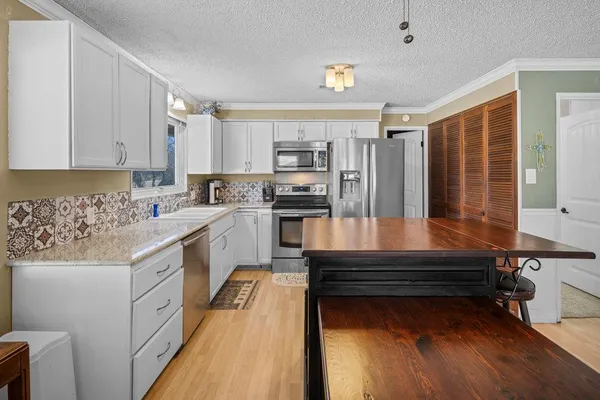 a kitchen with kitchen island granite countertop a sink cabinets and stainless steel appliances