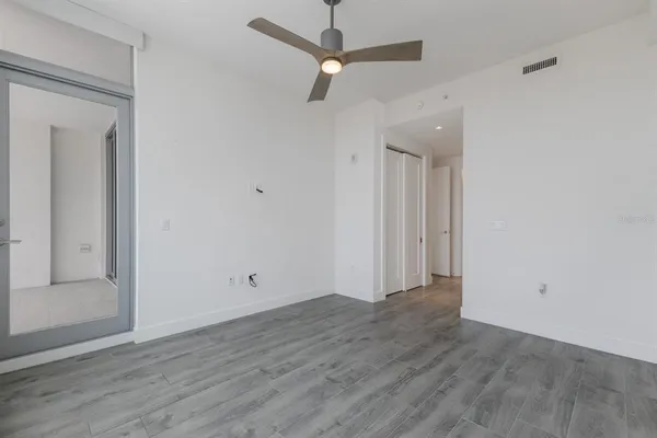 an empty room with wooden floor fan and windows