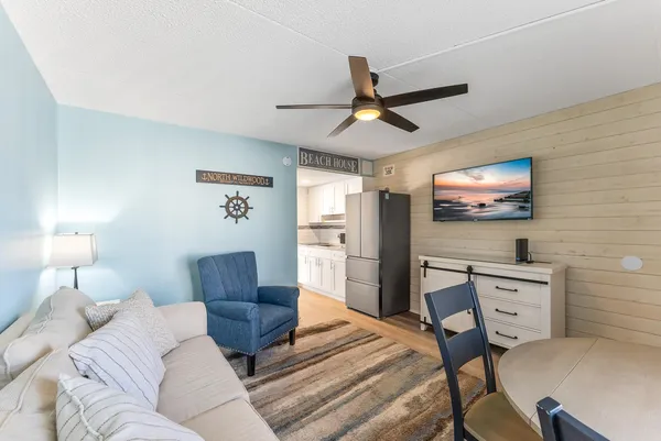 a living room with furniture a flat screen tv and a ceiling fan