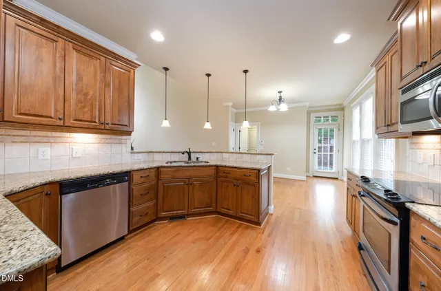 a large kitchen with stainless steel appliances granite countertop a stove a sink dishwasher and a microwave oven with wooden floor