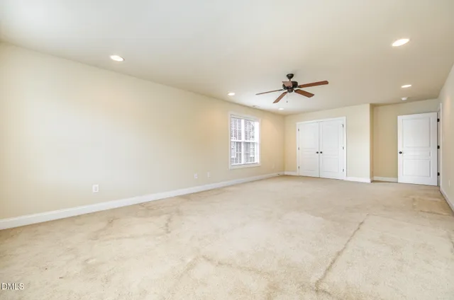 an empty room with a ceiling fan and window