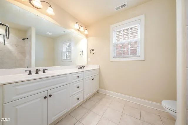a bathroom with a double vanity sink a toilet and a mirror