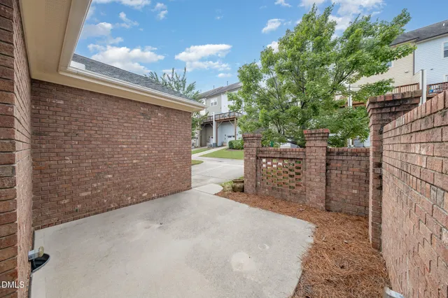 a view of a brick house with a large tree and wooden fence