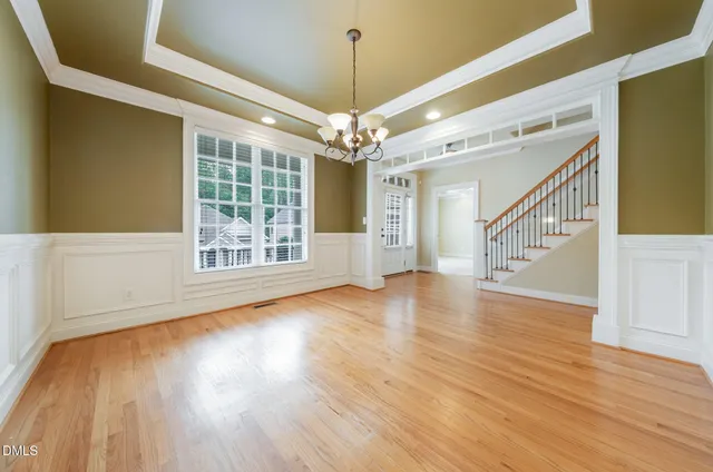 a view of a room with wooden floor chandelier and windows