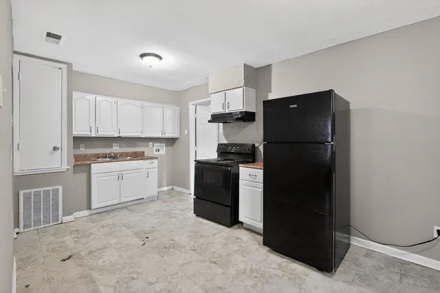 a kitchen with a refrigerator stove and white cabinets