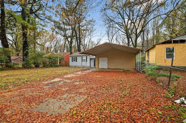 a backyard of a house with large trees and barbeque oven