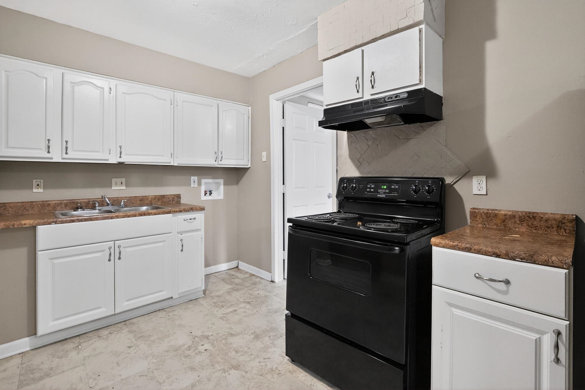 3981 Maynard Drive Memphis, TN 38109 - Photo 9 of 31 Kitchen with electric range, dark countertops, white cabinetry, and under cabinet range hood