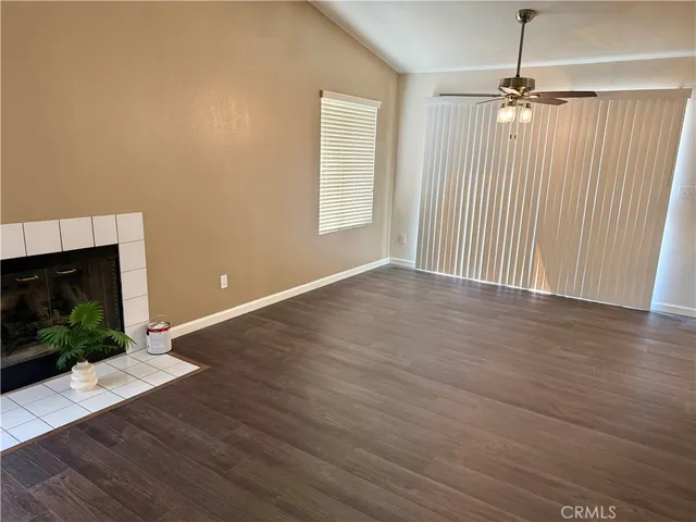 an empty room with wooden floor fireplace and windows