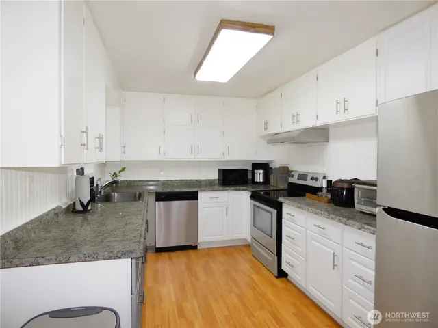 a kitchen with stainless steel appliances granite countertop a sink stove and cabinets
