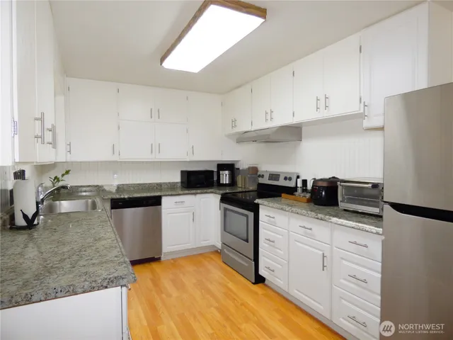 a kitchen with granite countertop white cabinets and white appliances