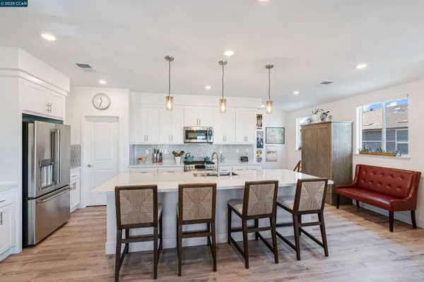 a kitchen with stainless steel appliances granite countertop a dining table chairs refrigerator and microwave