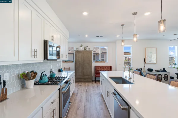 a kitchen with a refrigerator a sink a stove and white cabinets with wooden floor