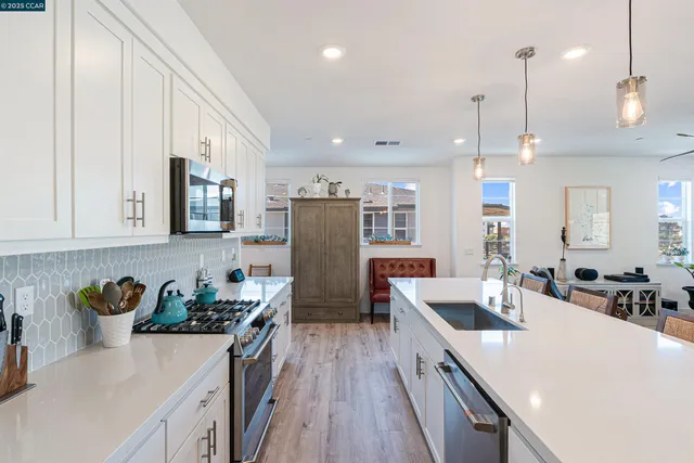 a kitchen with a refrigerator a sink a stove and white cabinets with wooden floor
