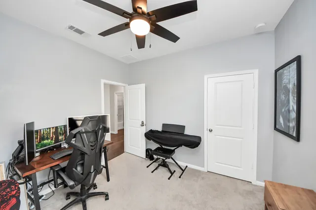 a view of a workspace with furniture and a ceiling fan