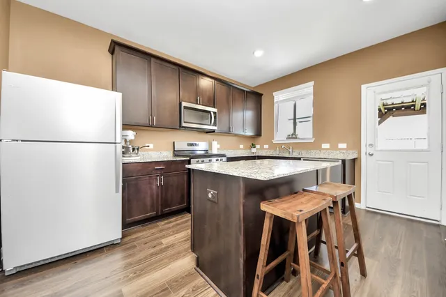 a kitchen with a refrigerator a stove a sink and a oven with wooden floor