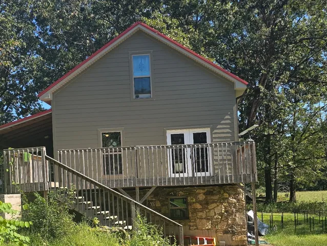 a view of an empty room with wooden floor and a ceiling fan