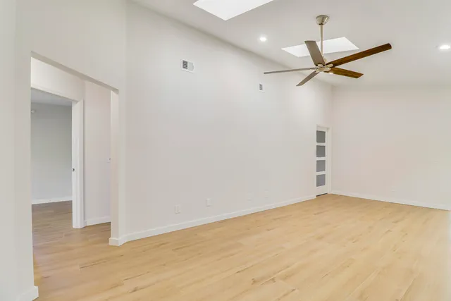 a view of empty room with wooden floor and fan