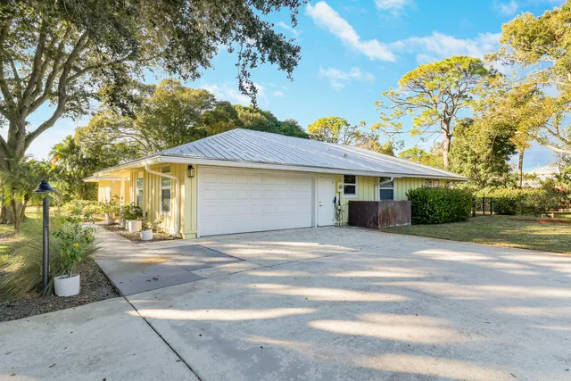 a front view of a house with a yard and potted plants