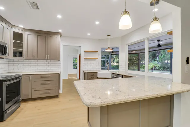 a large kitchen with kitchen island a large counter top space a sink stainless steel appliances and cabinets