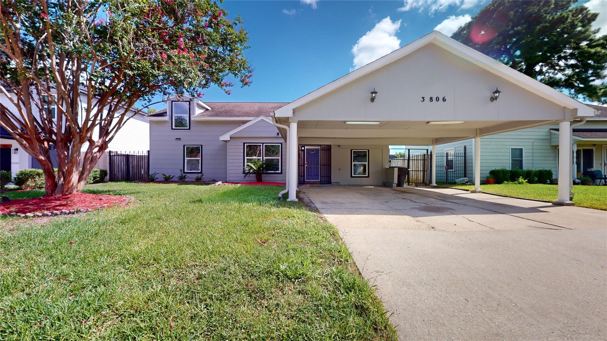 a view of a house with a small yard and a large tree
